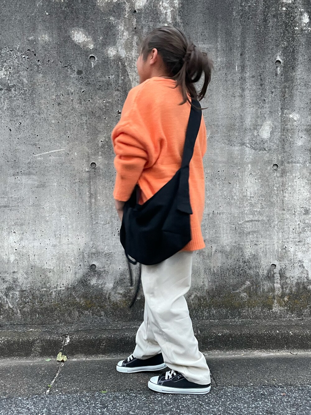 オレンジ系のニット/セーター、ホワイト系のその他パンツ、ブラック系のショルダーバッグを着用したキッズの秋コーディネートの3枚目の写真