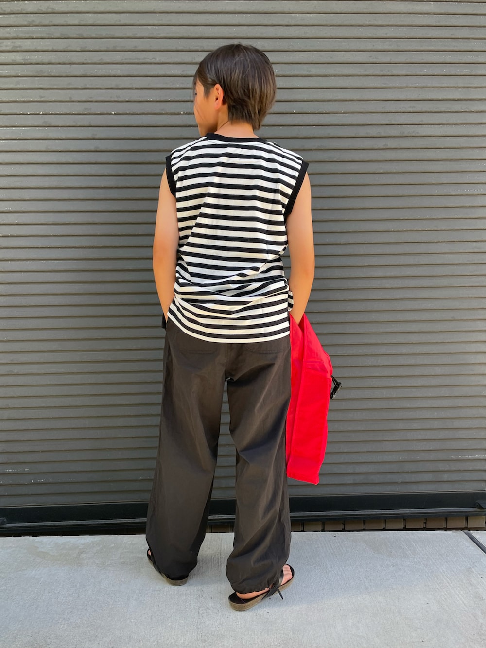 ブラック系のタンクトップ、ブラック系のその他パンツ、レッド系のエコバッグ/サブバッグを着用したキッズの夏コーディネートの4枚目の写真