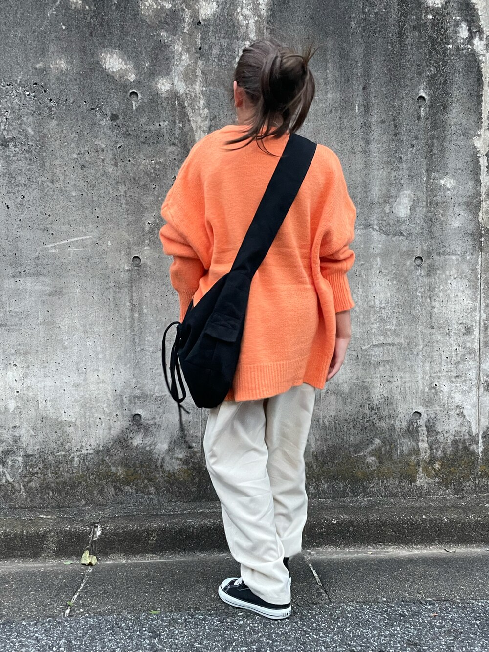 オレンジ系のニット/セーター、ホワイト系のその他パンツ、ブラック系のショルダーバッグを着用したキッズの秋コーディネートの4枚目の写真