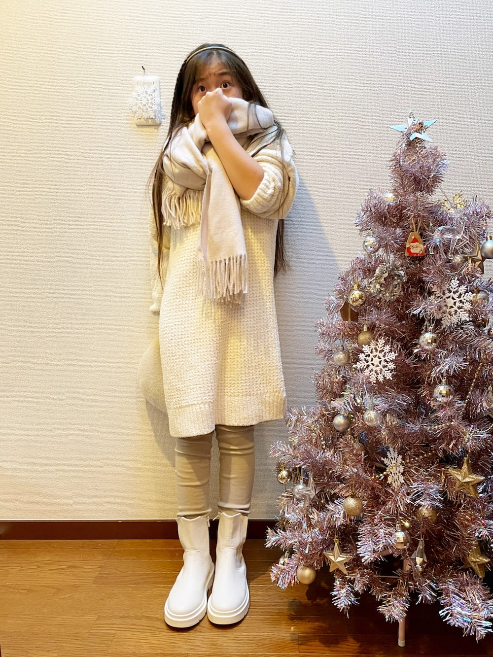 ホワイト系のワンピース、ベージュ系のハンドバッグ、ホワイト系のブーツを着用したキッズの冬コーディネートの2枚目の写真