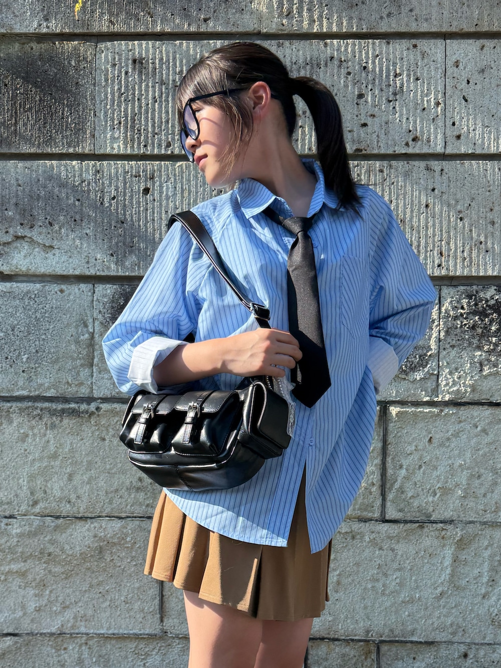 ベージュ系のスカート、ブラック系のショルダーバッグ、ホワイト系のスニーカーを着用したキッズの夏コーディネートの5枚目の写真