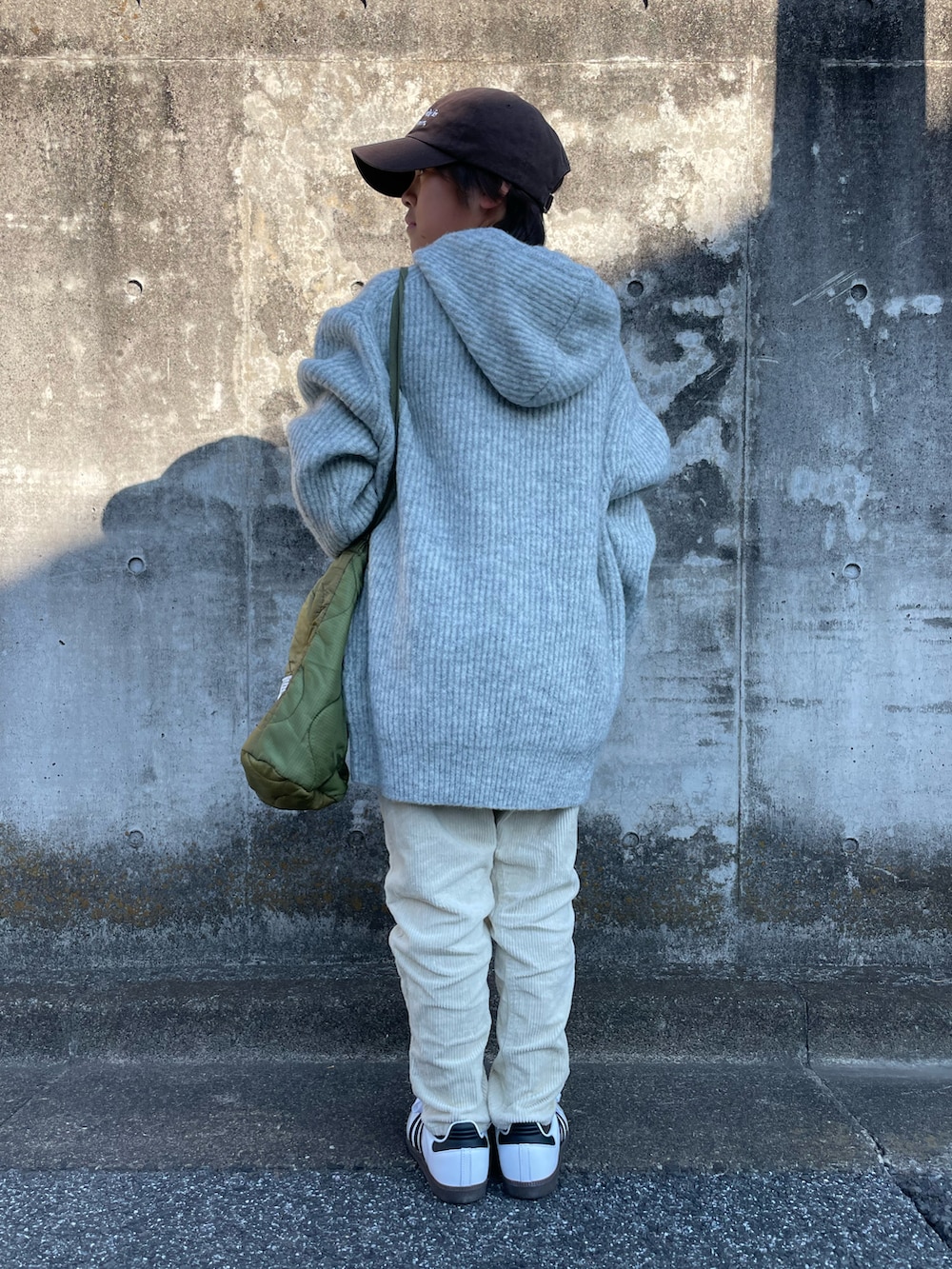 グレー系のニット/セーター、ホワイト系のその他パンツ、グリーン系のショルダーバッグを着用したキッズの冬コーディネートの3枚目の写真