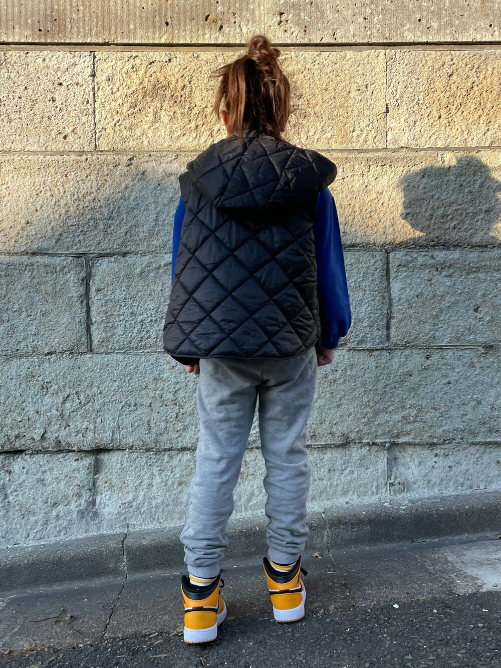 ブラック系のダウンベスト、ブルー系のスウェット、グレー系のその他パンツを着用したキッズの冬コーディネートの4枚目の写真