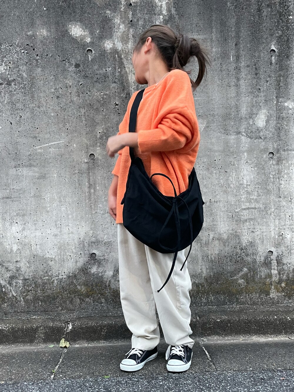 オレンジ系のニット/セーター、ホワイト系のその他パンツ、ブラック系のショルダーバッグを着用したキッズの秋コーディネートの2枚目の写真