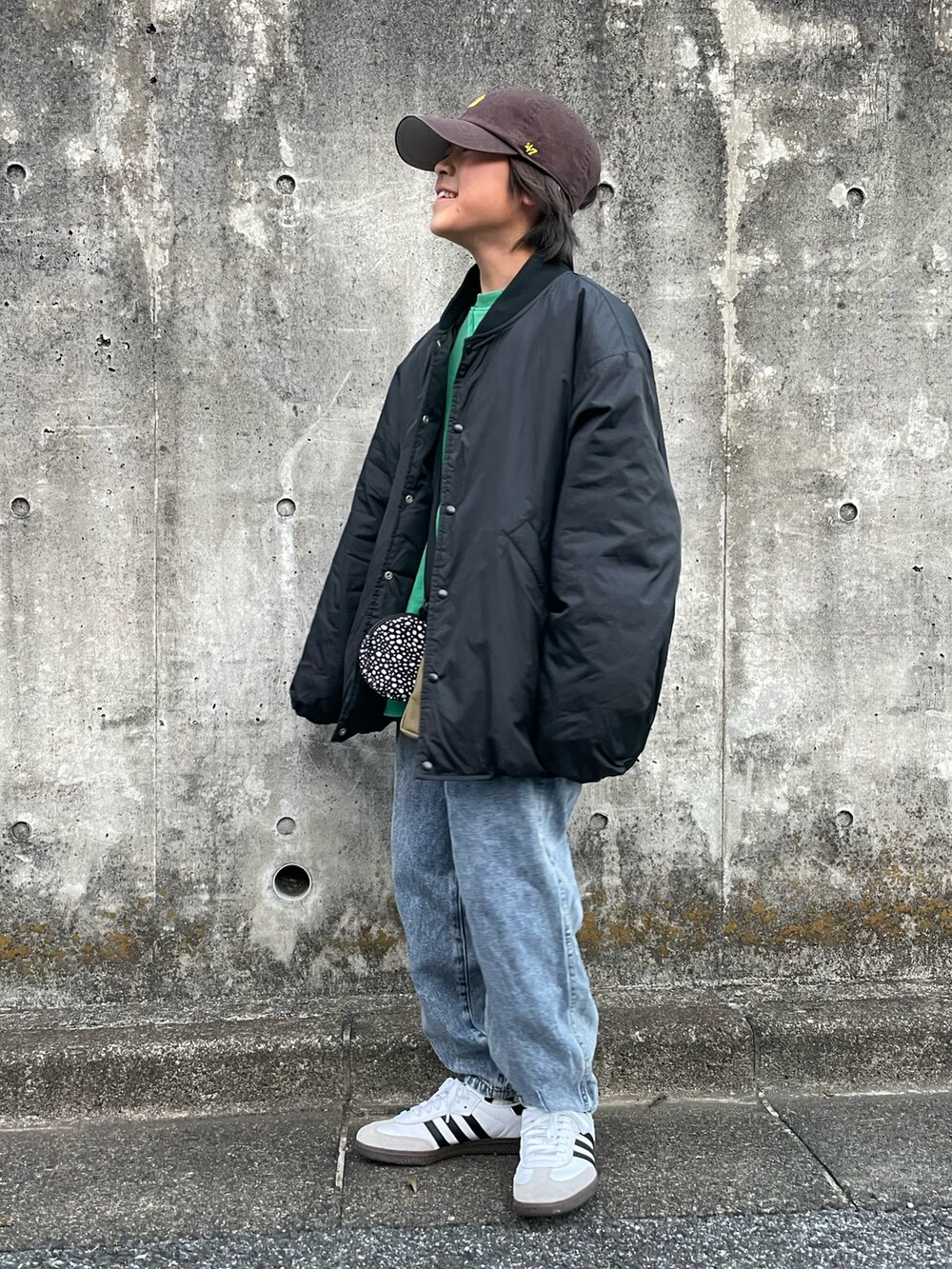 ブラック系のブルゾン、グリーン系のスウェット、ブルー系のデニムパンツを着用したキッズの冬コーディネートの2枚目の写真