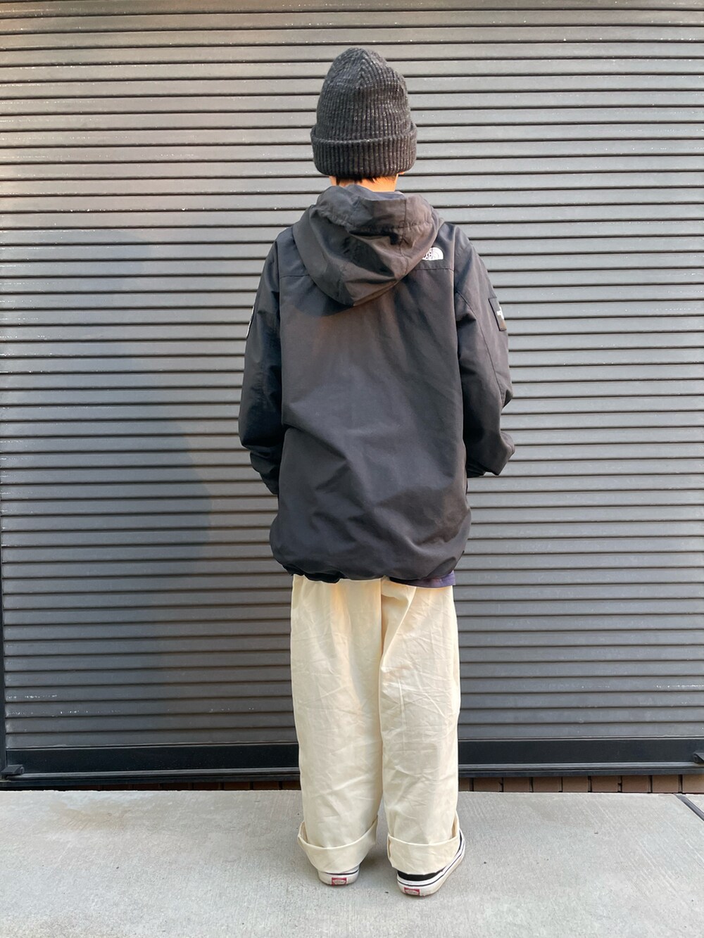 ブラック系のマウンテンパーカー、ホワイト系のカーゴパンツ、ブラック系のスニーカーを着用したキッズの秋コーディネートの2枚目の写真