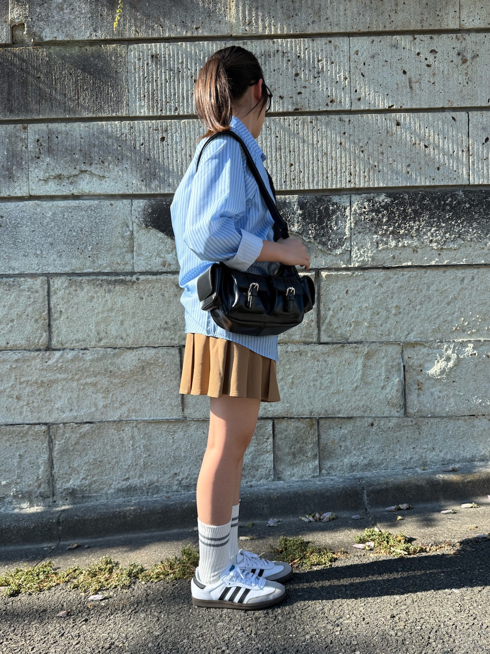 ベージュ系のスカート、ブラック系のショルダーバッグ、ホワイト系のスニーカーを着用したキッズの夏コーディネートの3枚目の写真