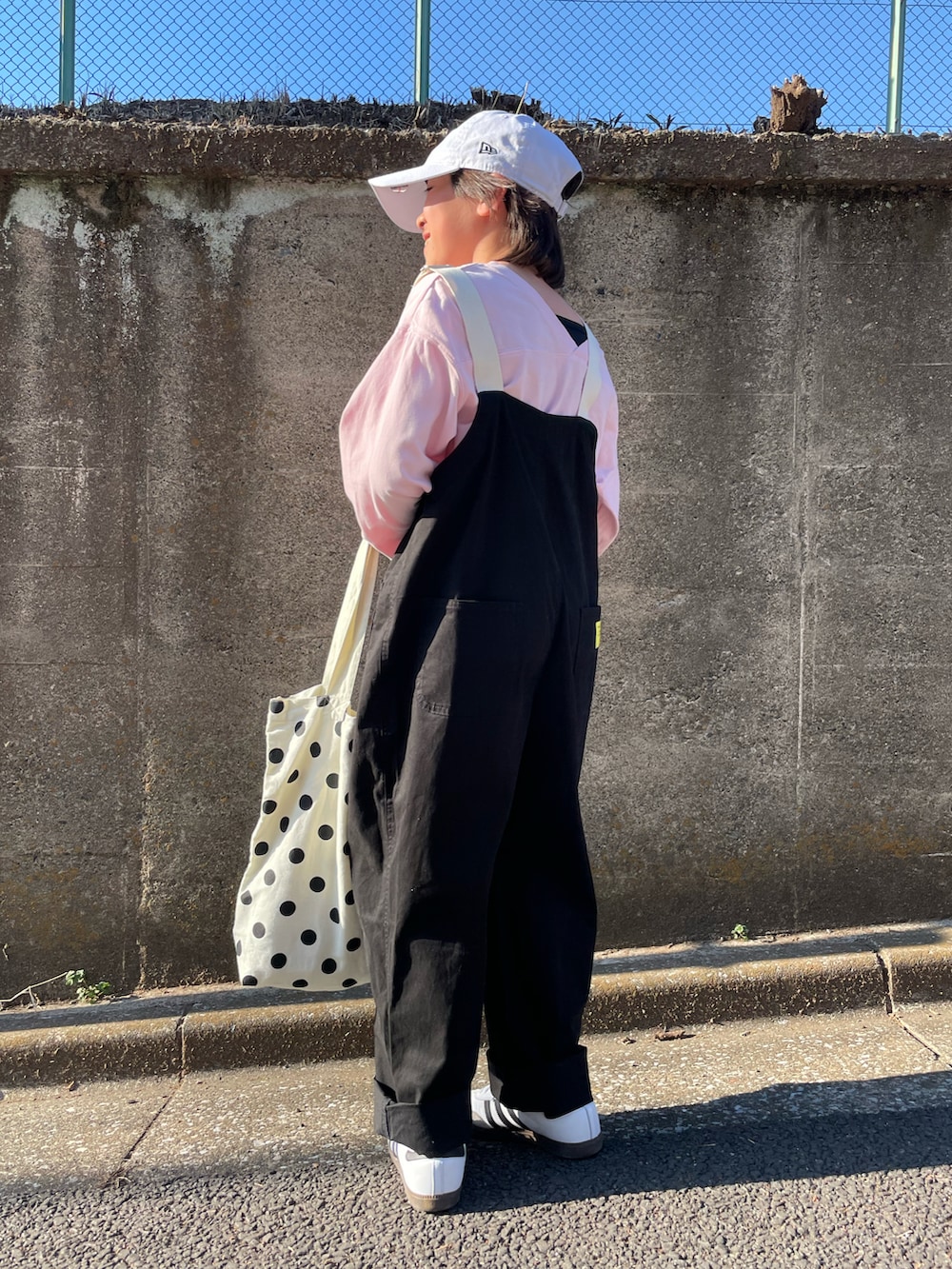 ブラック系のサロペット/オーバーオール、ピンク系のTシャツ/カットソー、ホワイト系のトートバッグを着用したキッズの春コーディネートの3枚目の写真