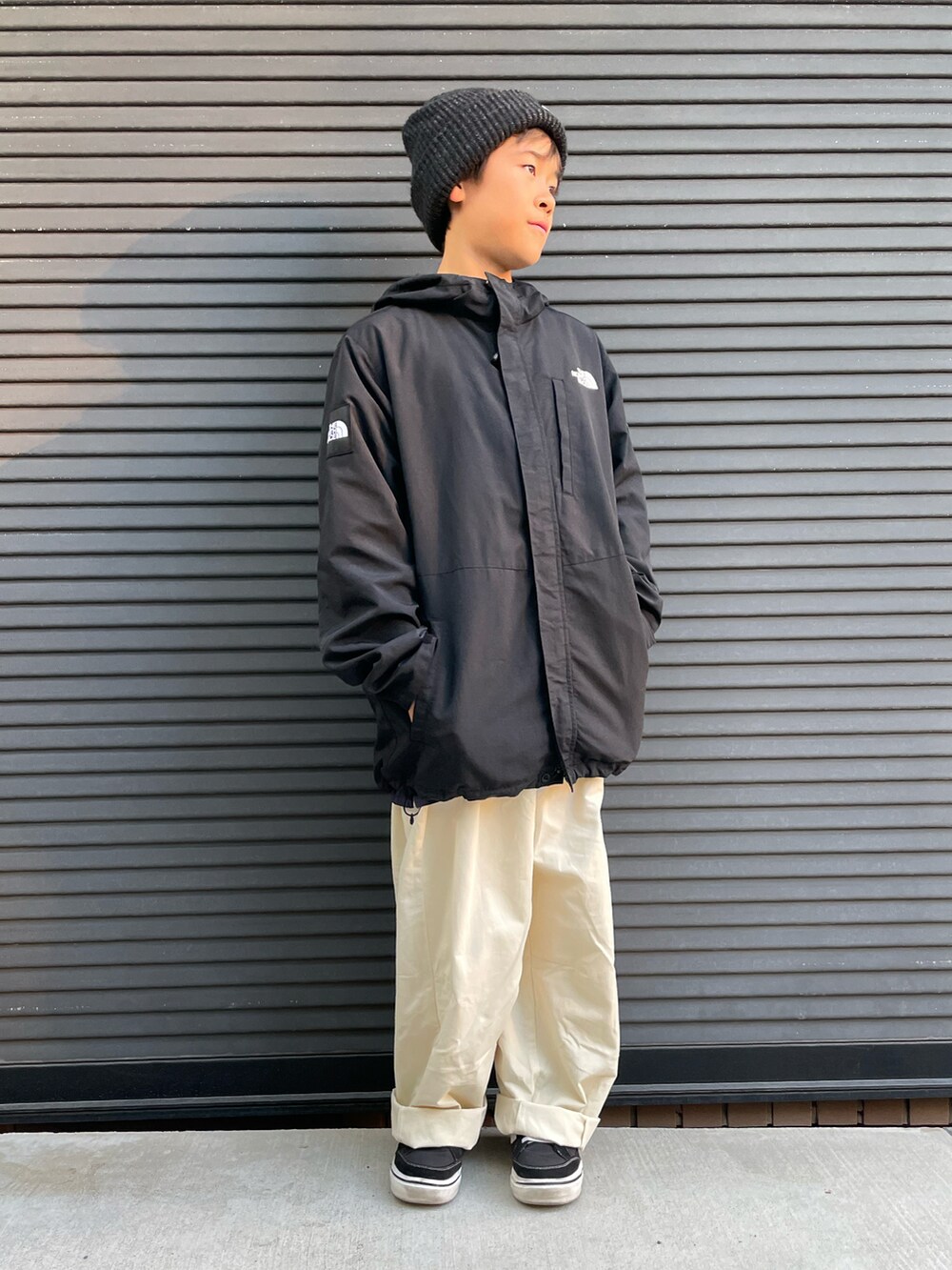 ブラック系のマウンテンパーカー、ホワイト系のカーゴパンツ、ブラック系のスニーカーを着用したキッズの秋コーディネートの3枚目の写真