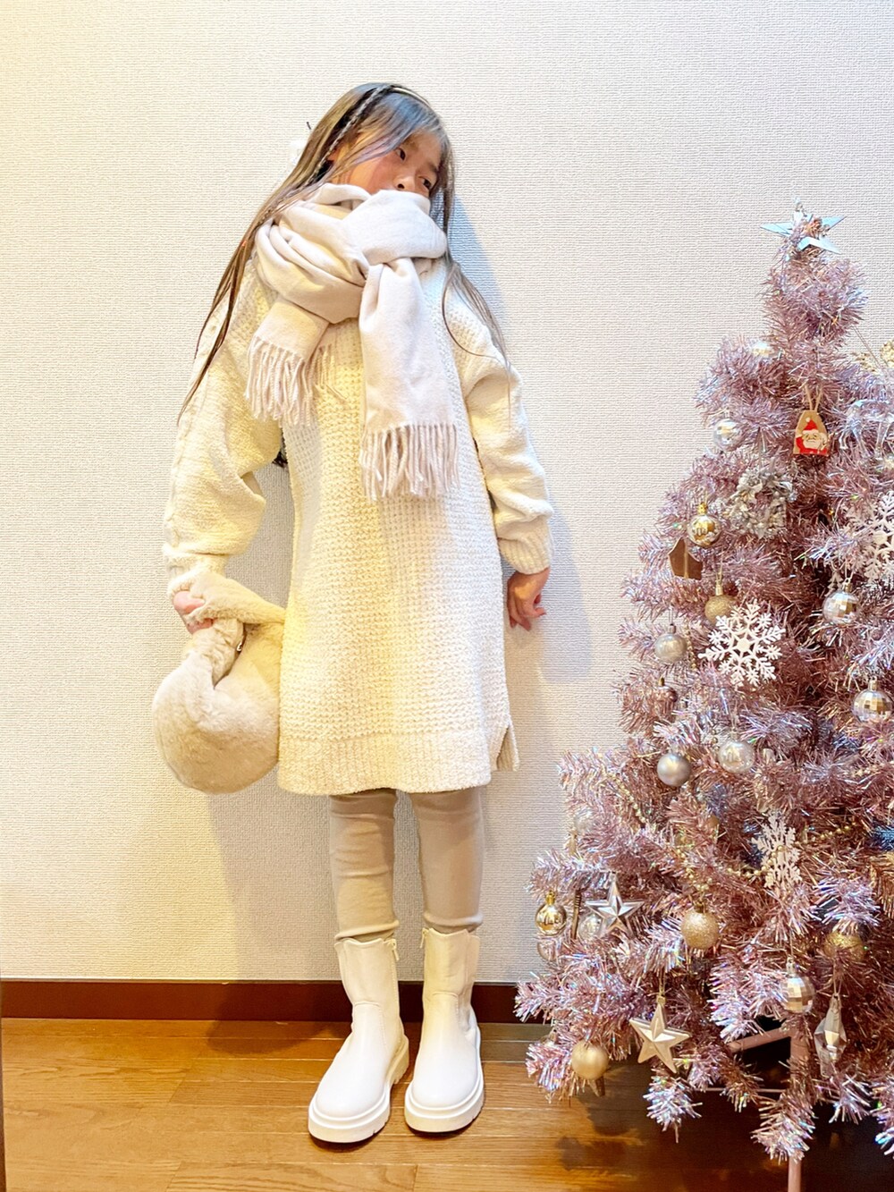 ホワイト系のワンピース、ベージュ系のハンドバッグ、ホワイト系のブーツを着用したキッズの冬コーディネートの3枚目の写真