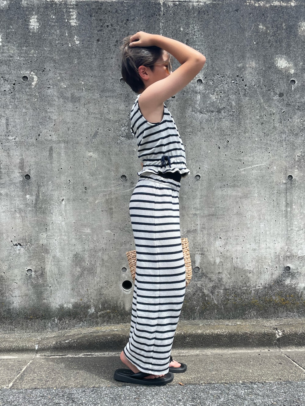 ホワイト系のアンサンブル、ベージュ系のかごバッグ、ブラック系のサンダルを着用したキッズの夏コーディネートの2枚目の写真