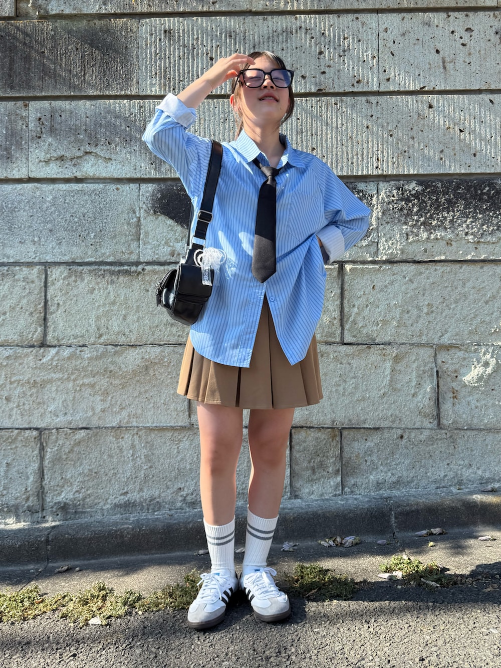 ベージュ系のスカート、ブラック系のショルダーバッグ、ホワイト系のスニーカーを着用したキッズの夏コーディネートの4枚目の写真