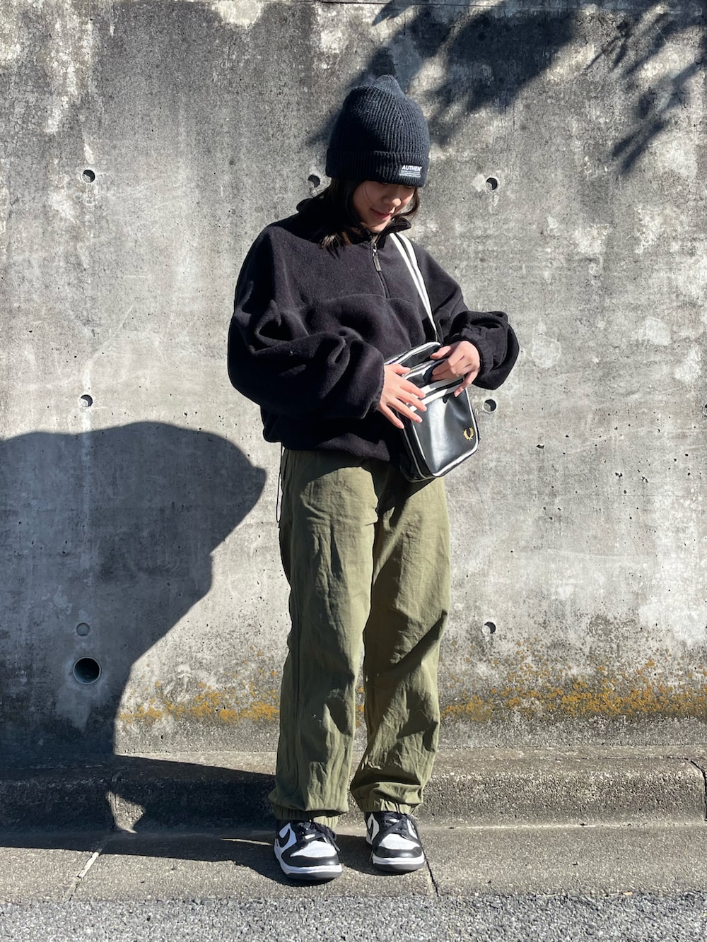 ブラック系のショルダーバッグ、ブラック系のトップス、グリーン系のカーゴパンツを着用したキッズの秋コーディネートの4枚目の写真