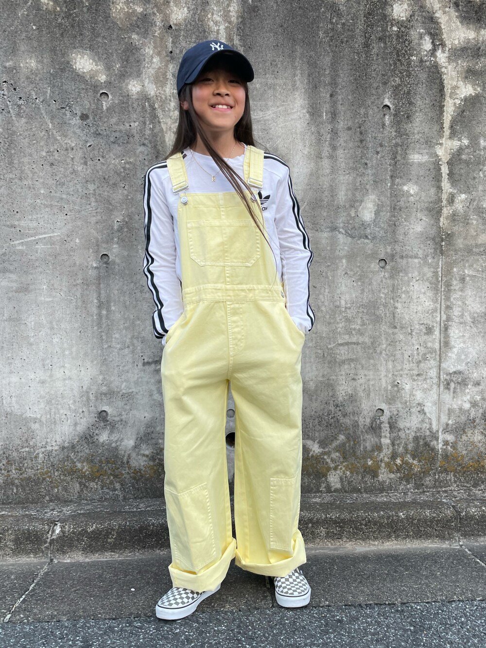 イエロー系のサロペット/オーバーオール、ホワイト系のTシャツ/カットソー、グリーン系のスニーカーを着用したキッズの春コーディネートの5枚目の写真