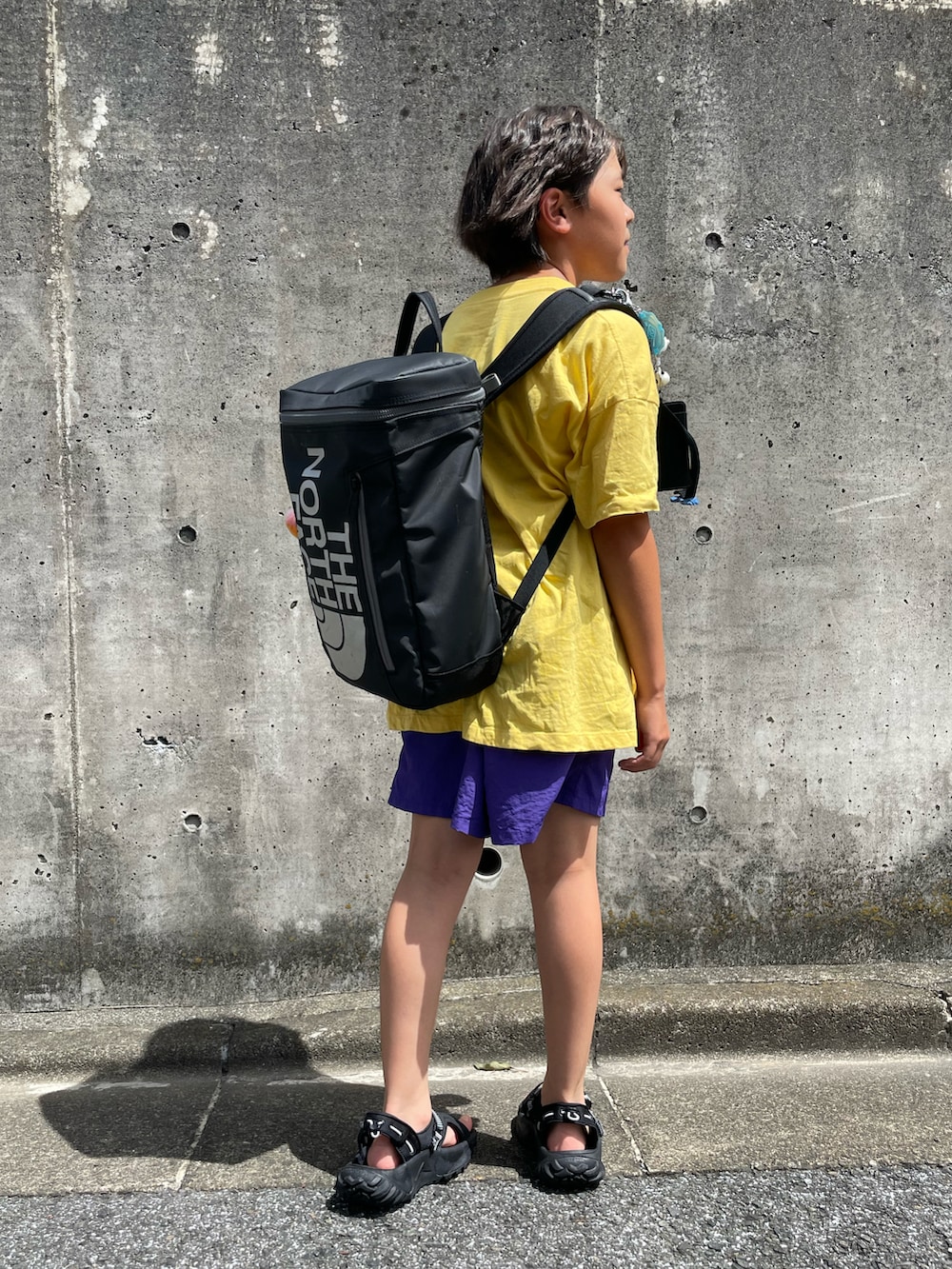 イエロー系のTシャツ/カットソー、パープル系のその他パンツ、ブラック系のバックパック/リュックを着用したキッズの夏コーディネートの3枚目の写真