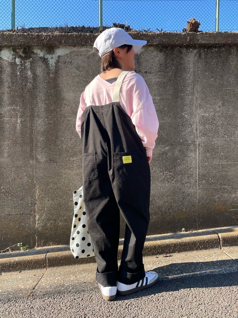 ブラック系のサロペット/オーバーオール、ピンク系のTシャツ/カットソー、ホワイト系のトートバッグを着用したキッズの春コーディネートの4枚目の写真