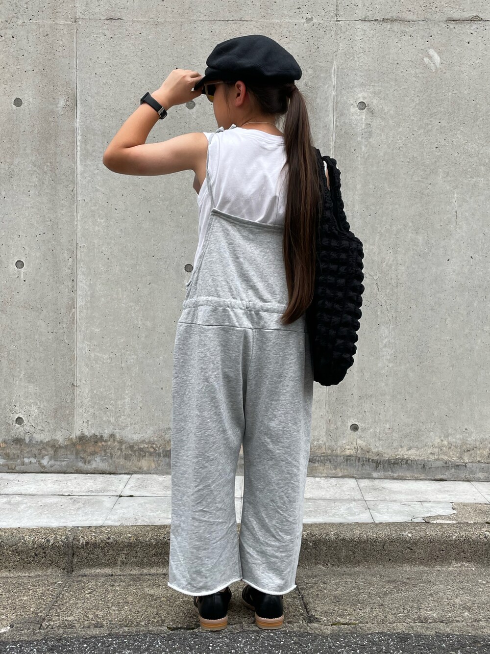 グレー系のオールインワン・サロペット、ブラック系のトートバッグ、ブラック系のサンダルを着用したキッズの夏コーディネートの2枚目の写真