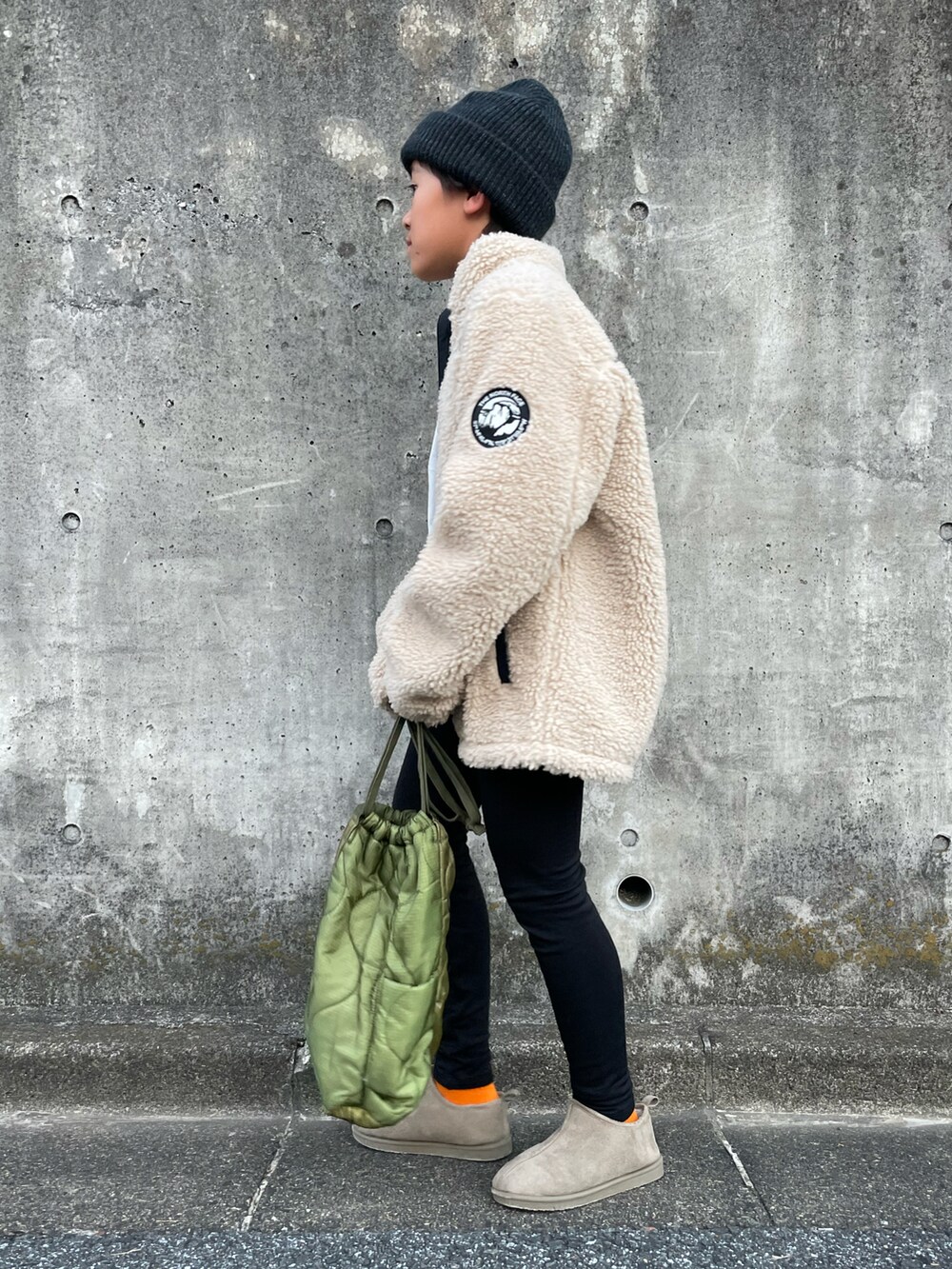 ベージュ系のブルゾン、ホワイト系のTシャツ/カットソー、グリーン系のショルダーバッグを着用したキッズの秋コーディネートの2枚目の写真