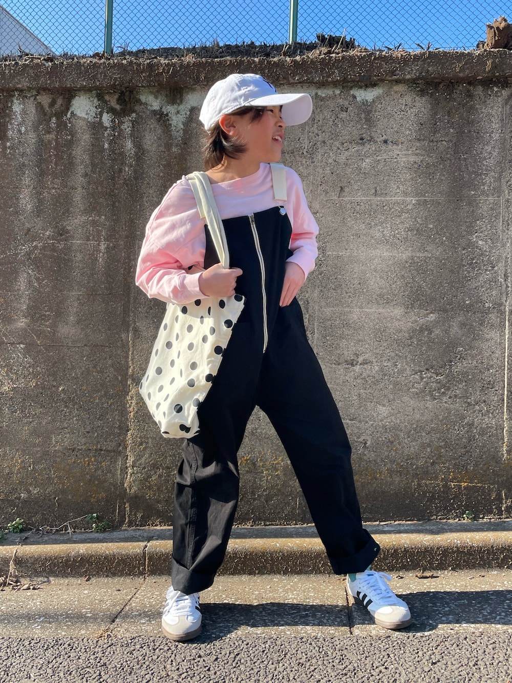 ブラック系のサロペット/オーバーオール、ピンク系のTシャツ/カットソー、ホワイト系のトートバッグを着用したキッズの春コーディネートの5枚目の写真
