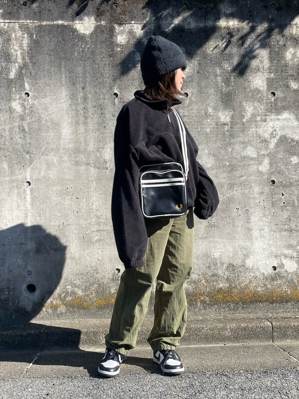 ブラック系のショルダーバッグ、ブラック系のトップス、グリーン系のカーゴパンツを着用したキッズの秋コーディネートの2枚目の写真