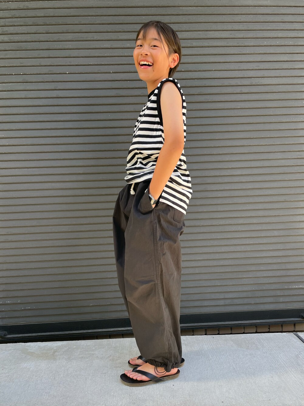 ブラック系のタンクトップ、ブラック系のその他パンツ、レッド系のエコバッグ/サブバッグを着用したキッズの夏コーディネートの3枚目の写真