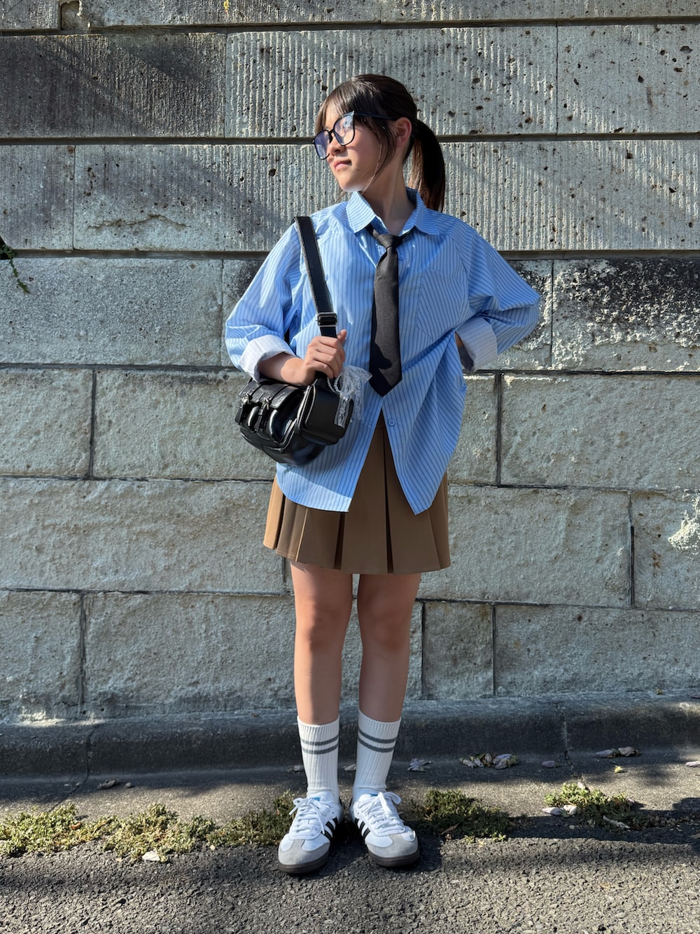 ベージュ系のスカート、ブラック系のショルダーバッグ、ホワイト系のスニーカーを着用したキッズの夏コーディネートの2枚目の写真