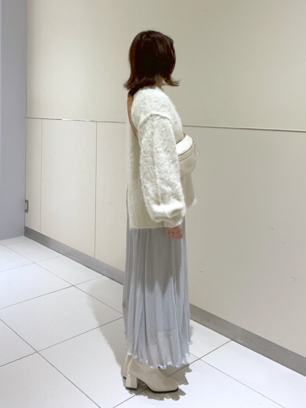 ホワイト系のニット/セーター、シルバー系のスカート、ホワイト系のブーツを着用したレディースの冬コーディネートの2枚目の写真