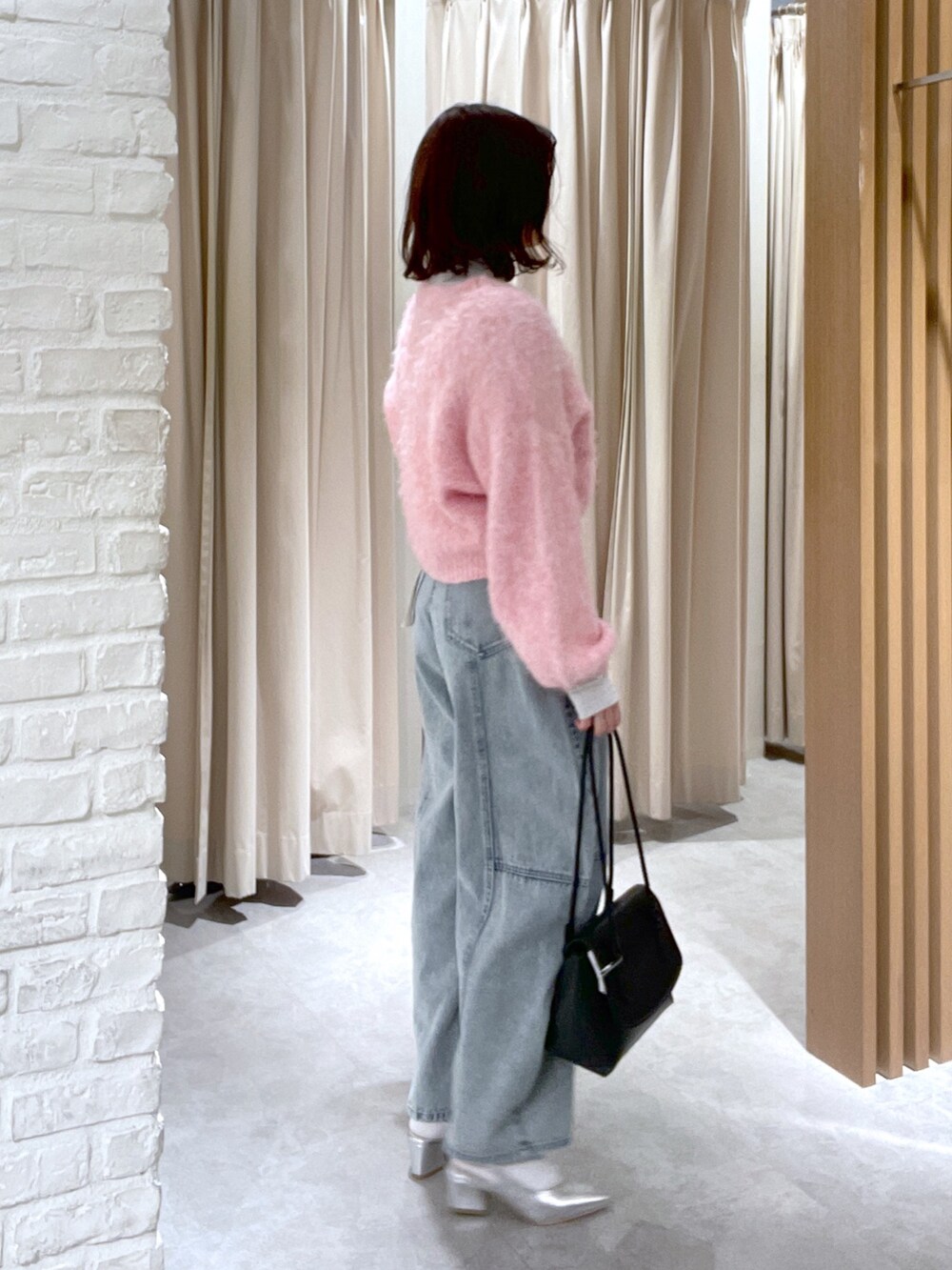 ブルー系のデニムパンツ、ブラック系のショルダーバッグ、シルバー系のパンプスを着用したレディースの冬コーディネートの6枚目の写真