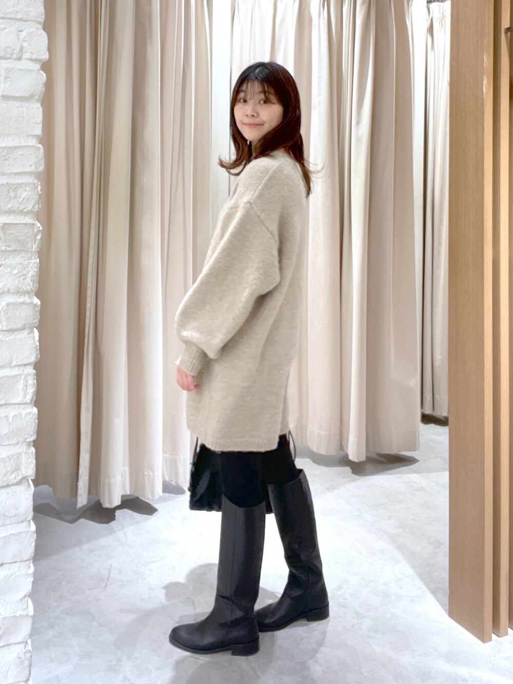 ベージュ系のワンピース、ブラック系のハンドバッグを着用したレディースの冬コーディネートの4枚目の写真