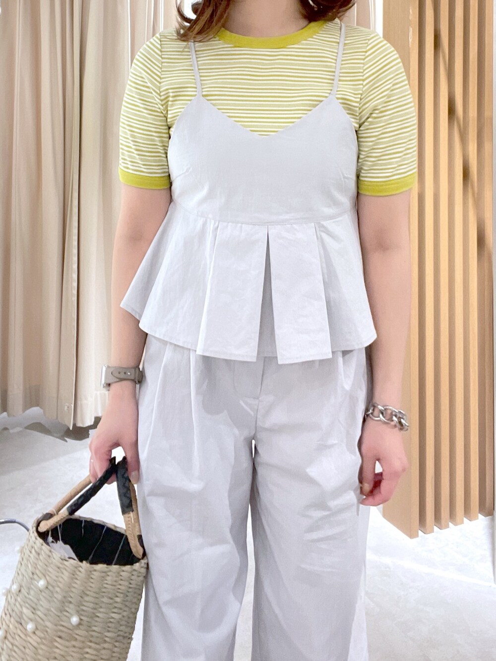 イエロー系のTシャツ/カットソー、グレー系のベスト、ブラック系のかごバッグを着用したレディースの春コーディネートの4枚目の写真