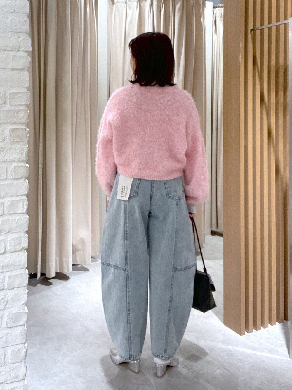 ブルー系のデニムパンツ、ブラック系のショルダーバッグ、シルバー系のパンプスを着用したレディースの冬コーディネートの5枚目の写真