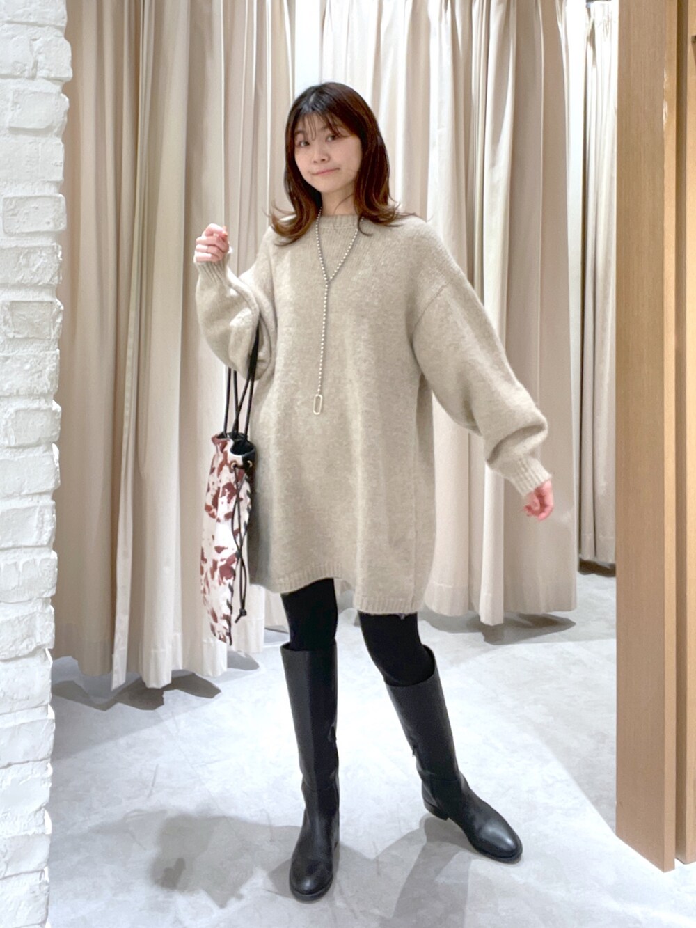 ベージュ系のワンピース、ブラック系のハンドバッグを着用したレディースの冬コーディネートの2枚目の写真