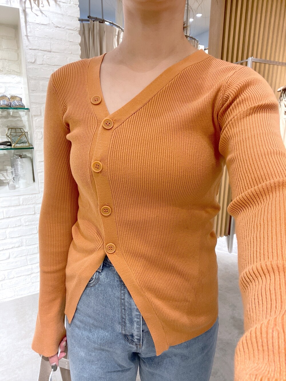 オレンジ系のカーディガン/ボレロ、ホワイト系のボディバッグ/ウエストポーチ、ブルー系のデニムパンツを着用したレディースの冬コーディネートの4枚目の写真