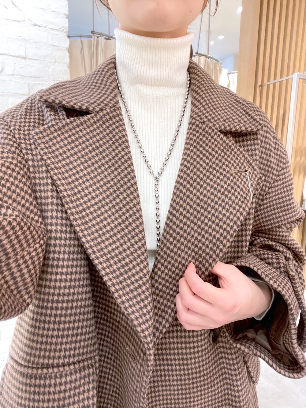 ベージュ系のピーコート、ホワイト系のニット/セーター、ブラック系のショルダーバッグを着用したレディースの冬コーディネートの5枚目の写真