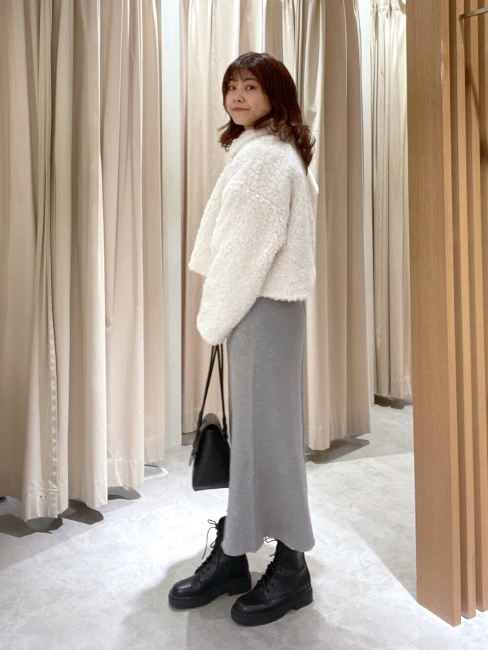 ホワイト系のブルゾン、グレー系のワンピース、ブラック系のブーツを着用したレディースの秋コーディネートの2枚目の写真