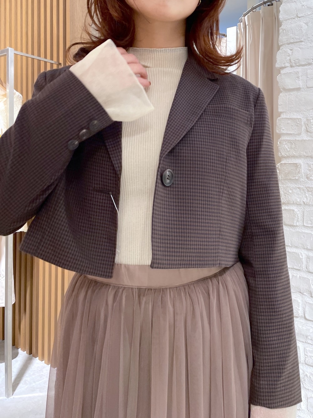 ブラウン系のテーラードジャケット、ホワイト系のニット/セーター、ブラウン系のスカートを着用したレディースの秋コーディネートの4枚目の写真