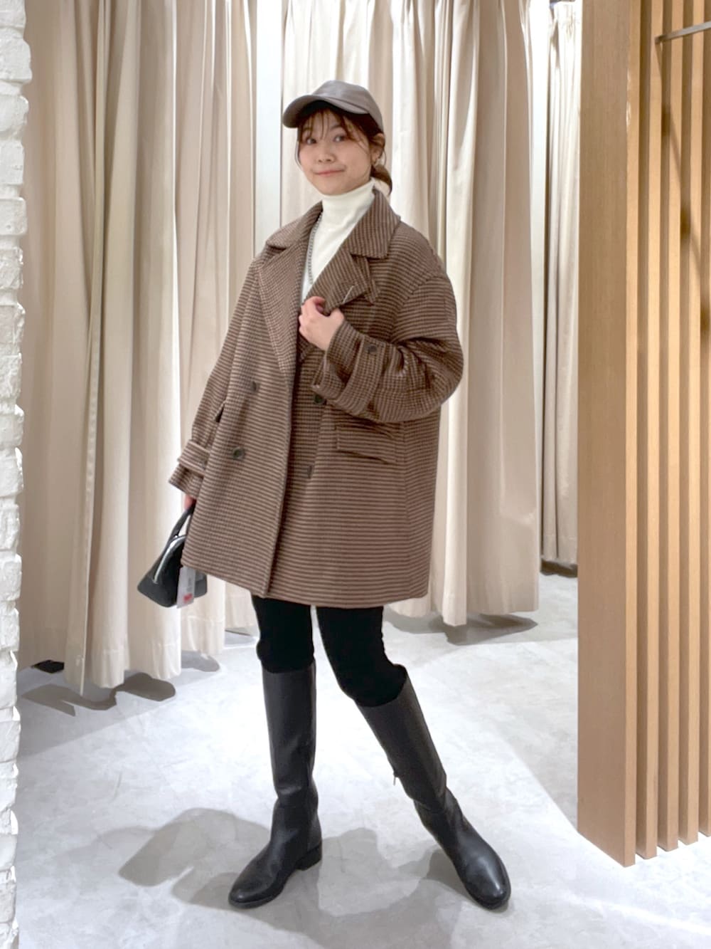 ベージュ系のピーコート、ホワイト系のニット/セーター、ブラック系のショルダーバッグを着用したレディースの冬コーディネートの2枚目の写真