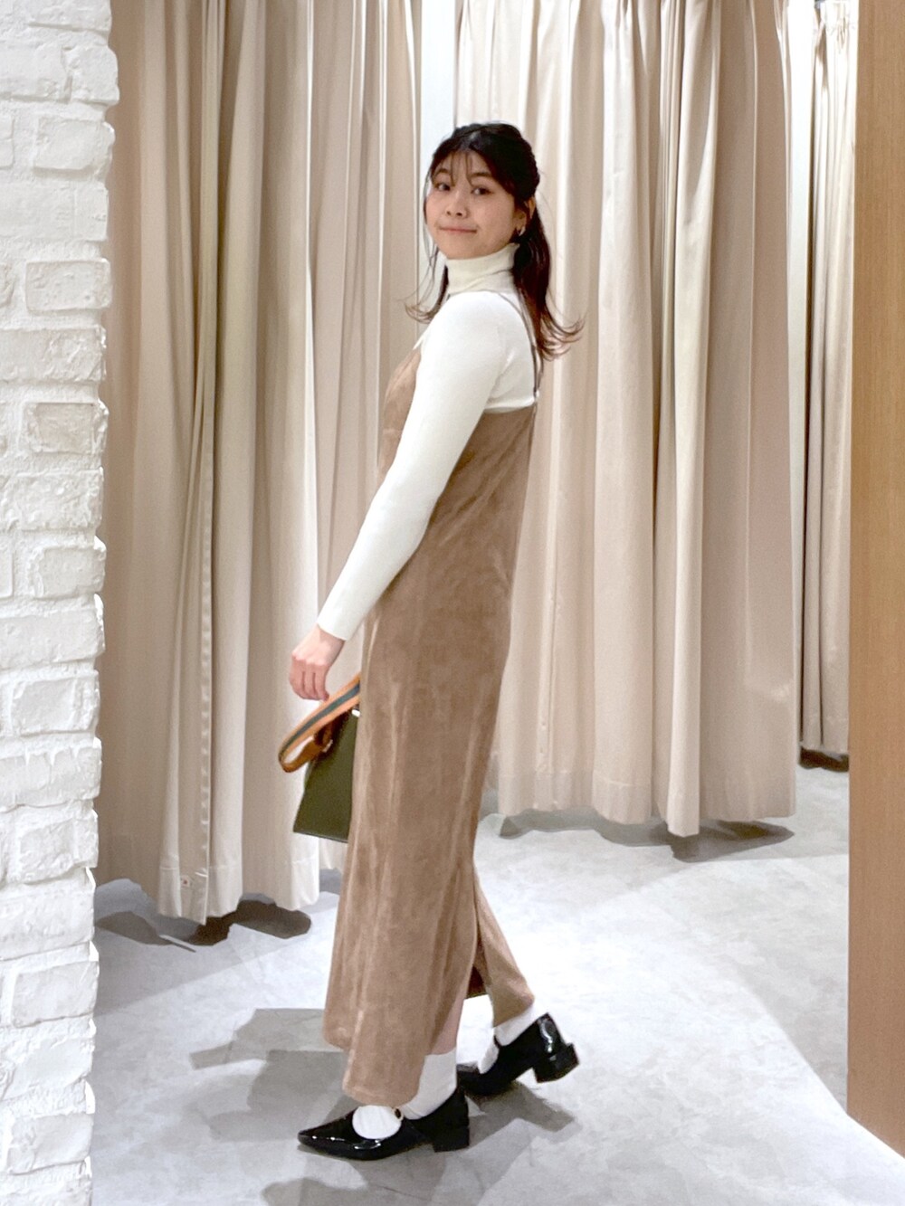 ホワイト系のニット/セーター、ブラウン系のワンピース、グリーン系のショルダーバッグを着用したレディースの冬コーディネートの3枚目の写真