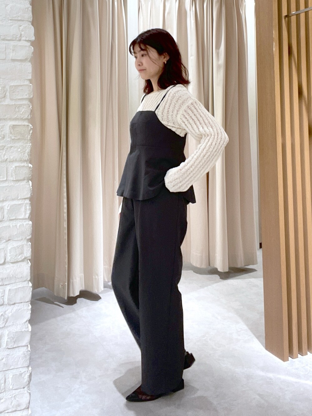 ホワイト系のニット/セーター、ブラック系のシャツ/ブラウス、ブラック系のスラックスを着用したレディースの春コーディネートの2枚目の写真