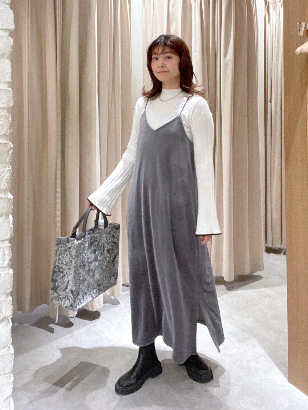 ホワイト系のニット/セーター、グレー系のワンピース、グレー系のトートバッグを着用したレディースの冬コーディネートの2枚目の写真