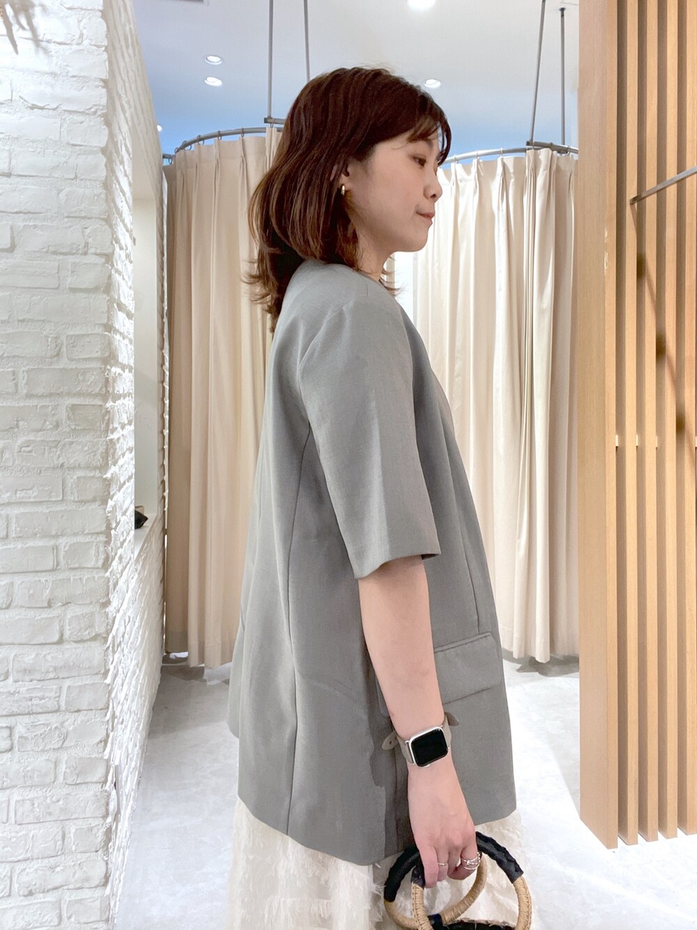 グレー系のノーカラージャケット、ホワイト系のワンピース、ブラック系のサンダルを着用したレディースの夏コーディネートの4枚目の写真
