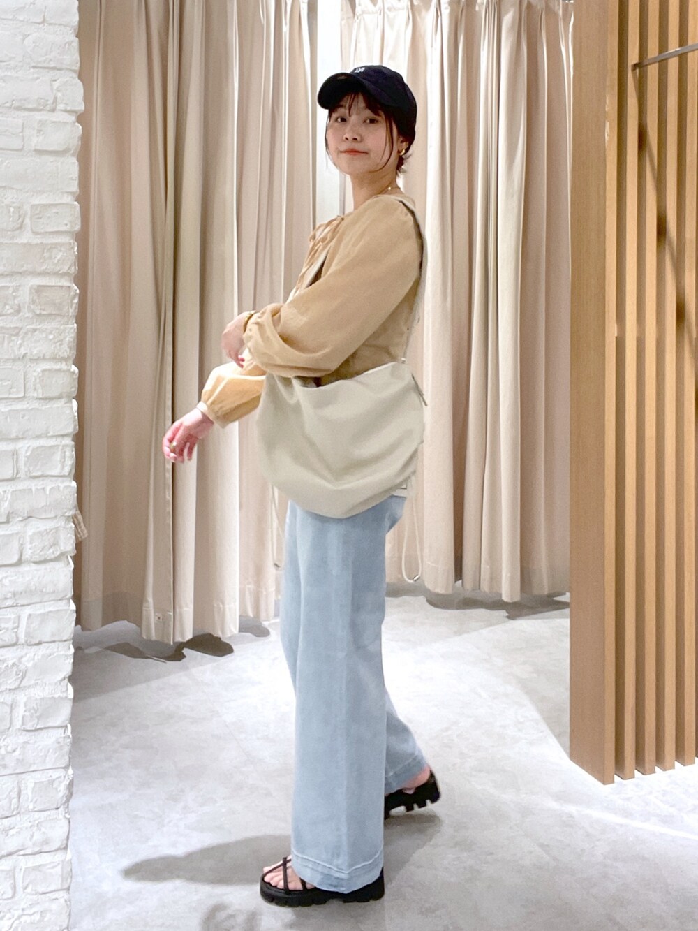 イエロー系のシャツ/ブラウス、ホワイト系のショルダーバッグ、ブルー系のデニムパンツを着用したレディースの春コーディネートの2枚目の写真