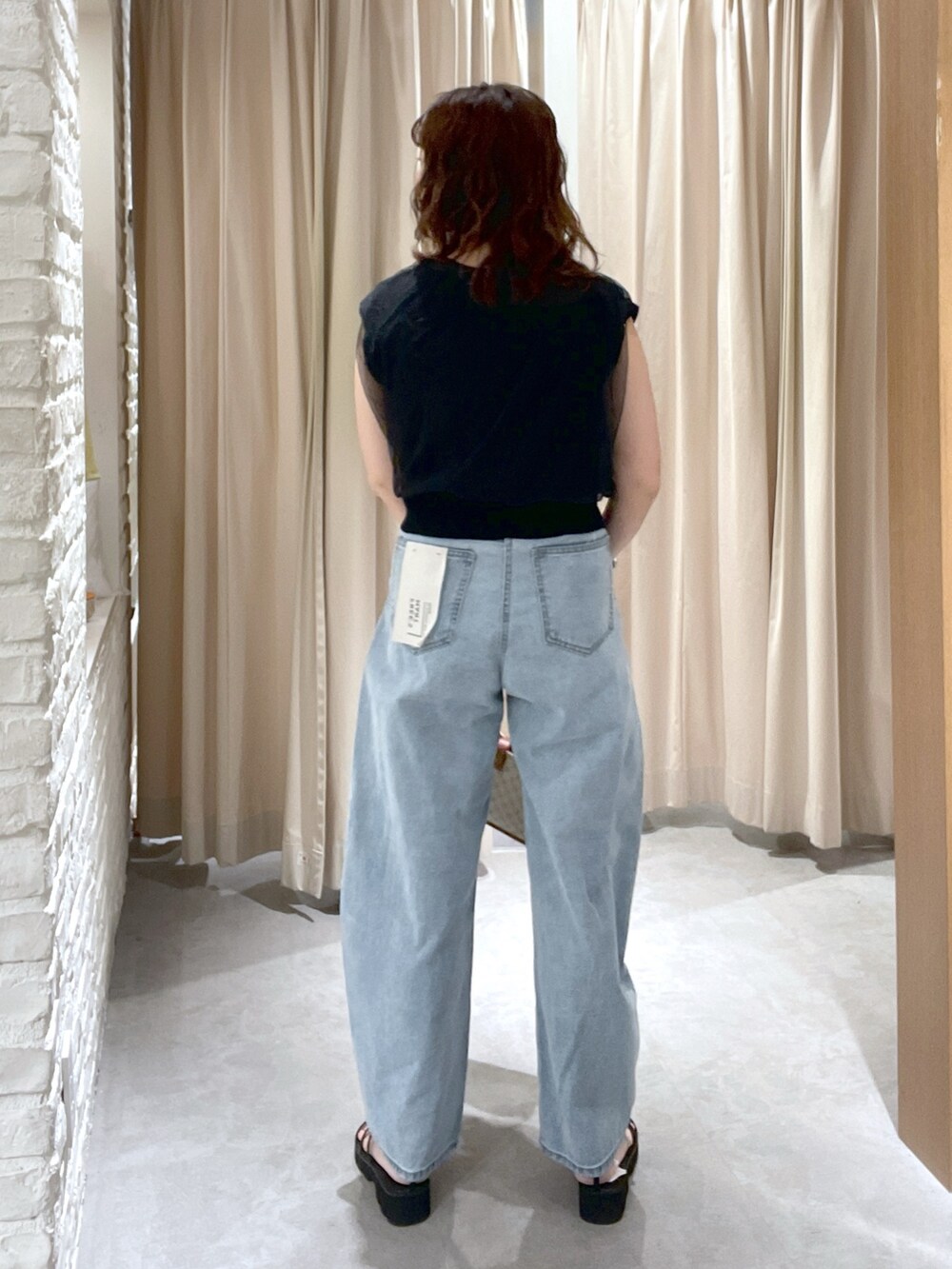 ブラック系のベスト、ブルー系のデニムパンツ、ブラック系のサンダルを着用したレディースの夏コーディネートの3枚目の写真