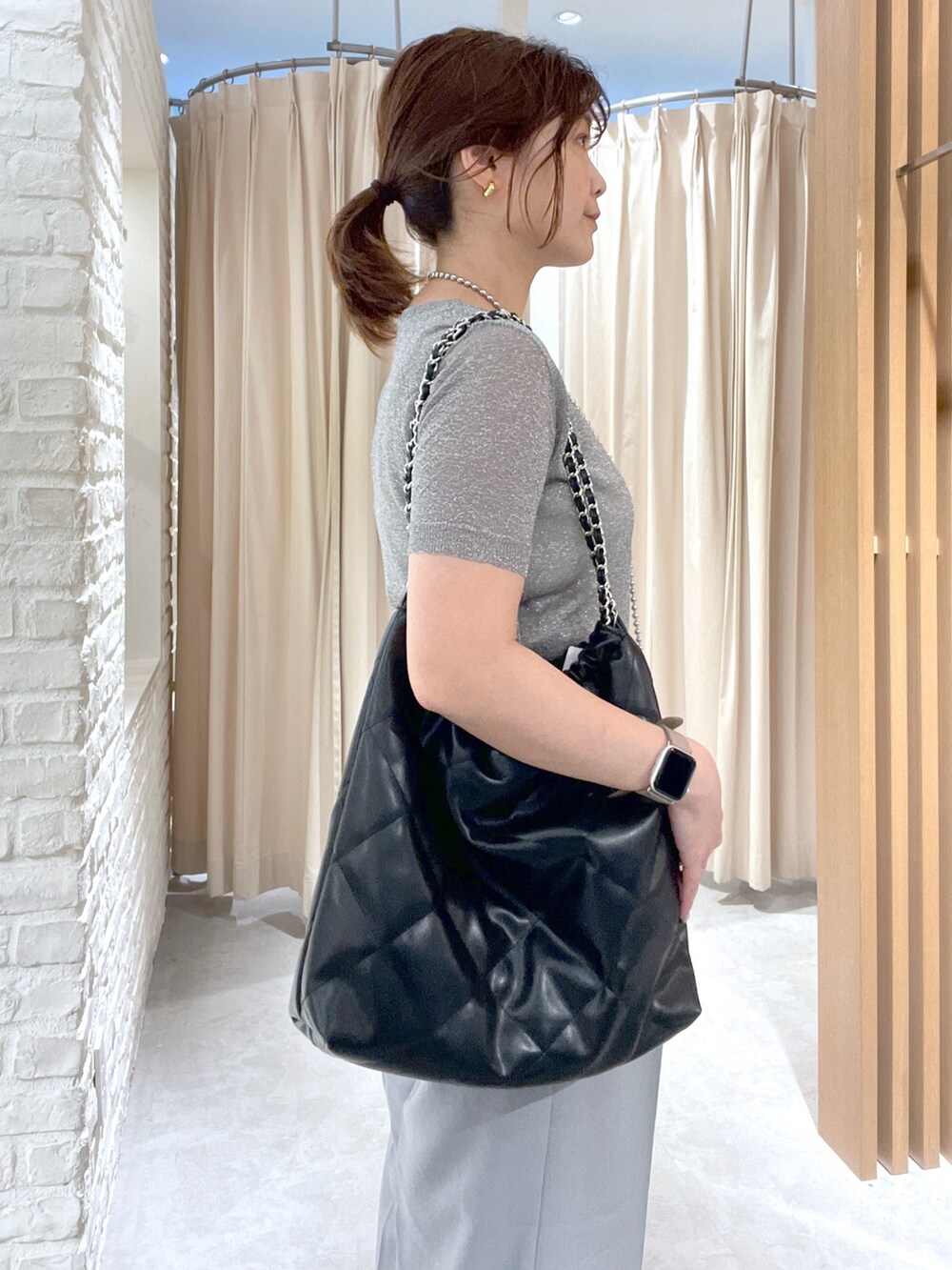 シルバー系のニット/セーター、グレー系のスラックス、ブラック系のサンダルを着用したレディースの夏コーディネートの4枚目の写真