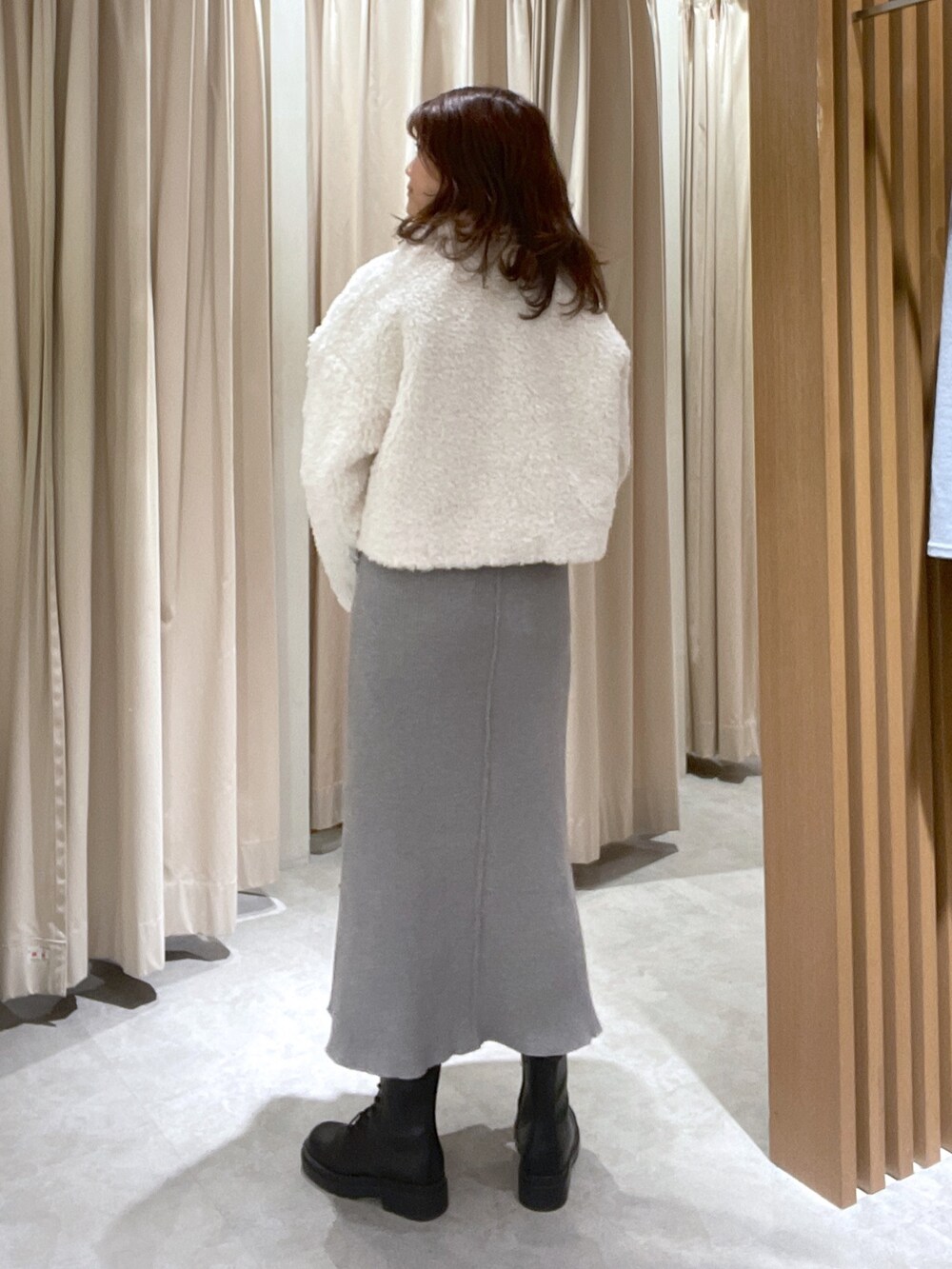 ホワイト系のブルゾン、グレー系のワンピース、ブラック系のブーツを着用したレディースの秋コーディネートの3枚目の写真