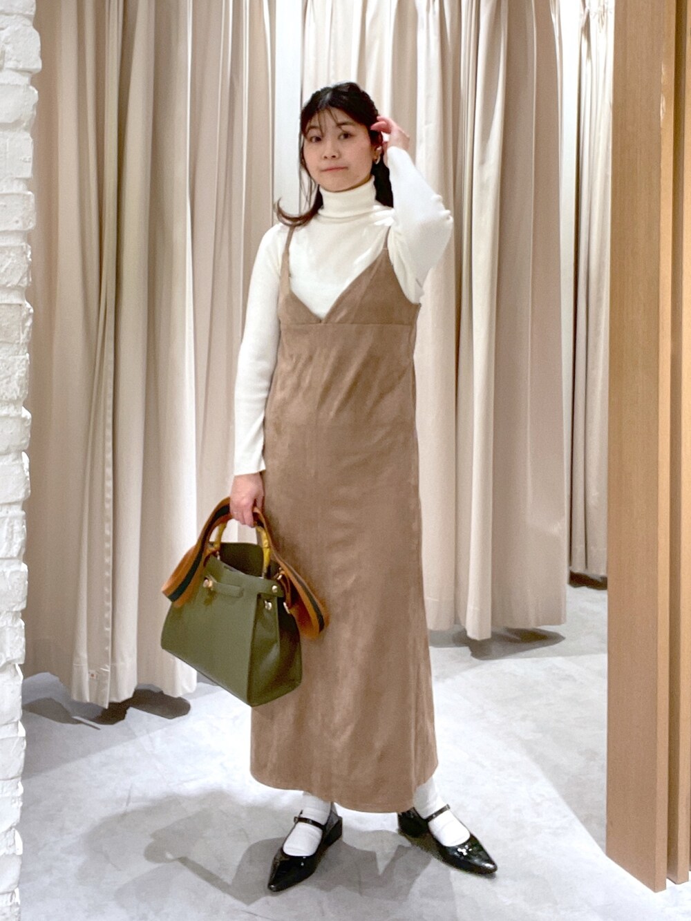 ホワイト系のニット/セーター、ブラウン系のワンピース、グリーン系のショルダーバッグを着用したレディースの冬コーディネートの2枚目の写真