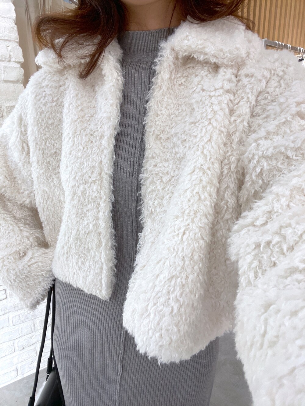 ホワイト系のブルゾン、グレー系のワンピース、ブラック系のブーツを着用したレディースの秋コーディネートの4枚目の写真