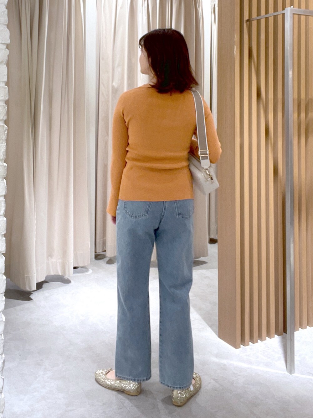 オレンジ系のカーディガン/ボレロ、ホワイト系のボディバッグ/ウエストポーチ、ブルー系のデニムパンツを着用したレディースの冬コーディネートの3枚目の写真