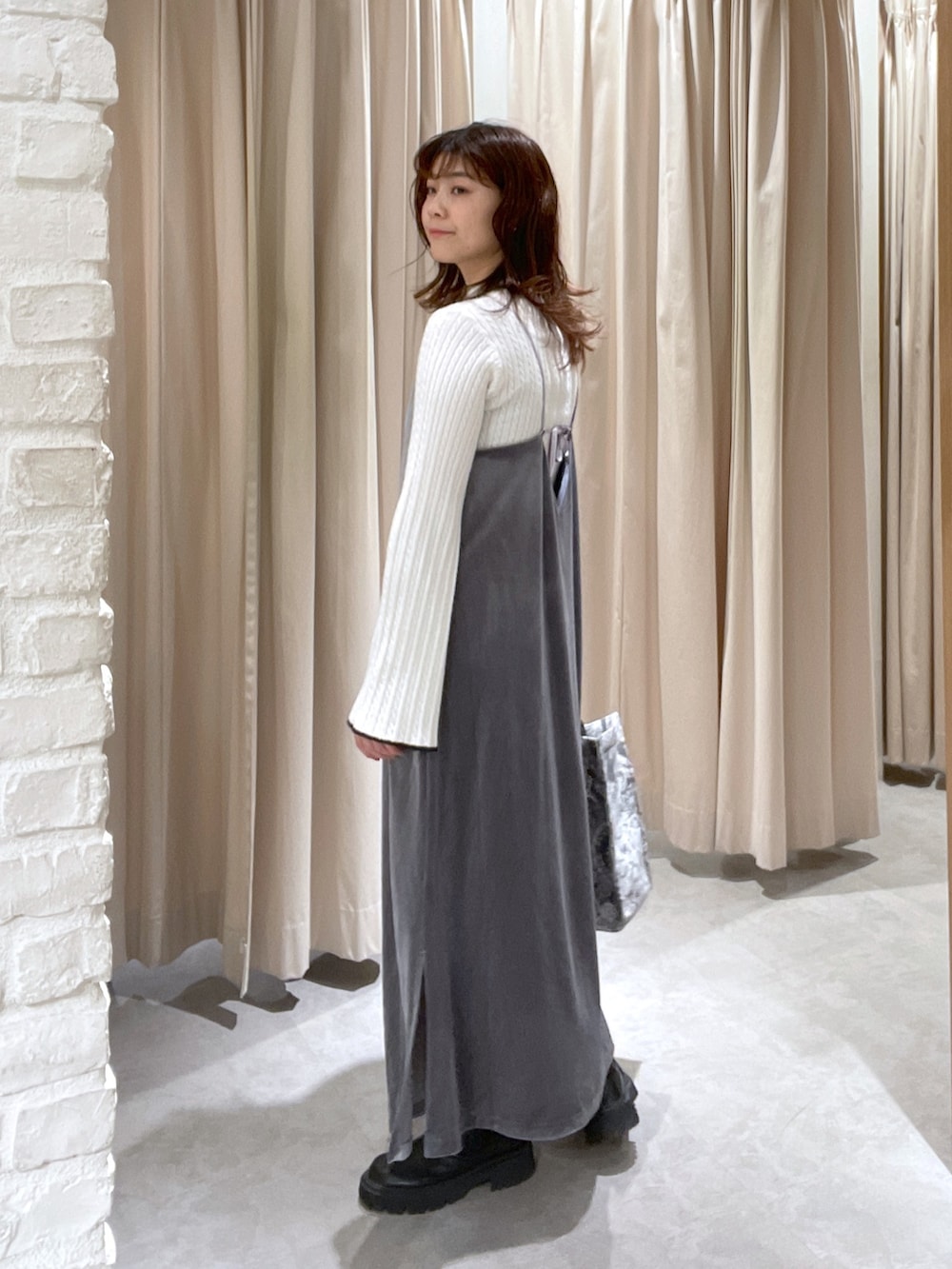 ホワイト系のニット/セーター、グレー系のワンピース、グレー系のトートバッグを着用したレディースの冬コーディネートの3枚目の写真