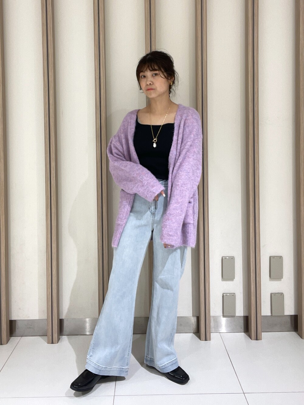 パープル系のカーディガン/ボレロ、ブラック系のTシャツ/カットソー、ブルー系のデニムパンツを着用したレディースの秋コーディネートの2枚目の写真